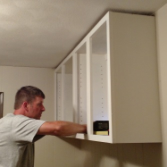 My husband hanging the newly painted cabinets!